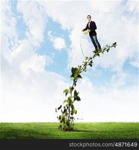 Make your income grow. Young man pouring water on growing tree concept