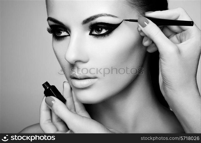 Makeup artist applies eye shadow. Beautiful woman face. Perfect makeup. Black and white photo