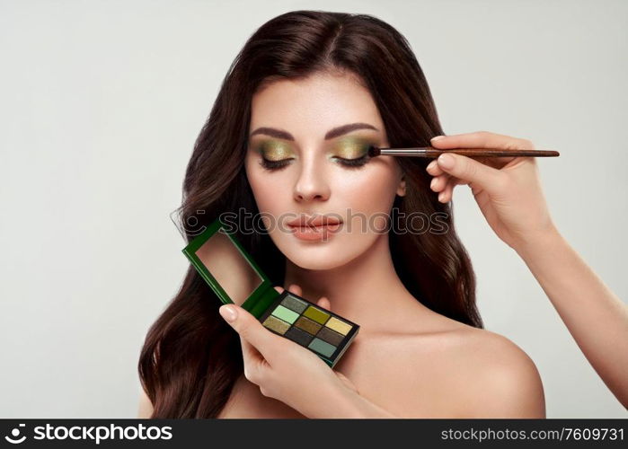 Makeup artist applies eye shadow. Beautiful woman face. Perfect makeup. Make-up detail. Beauty girl with perfect skin. Nails and manicure. Eye shadow palette