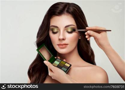 Makeup artist applies eye shadow. Beautiful woman face. Perfect makeup. Make-up detail. Beauty girl with perfect skin. Nails and manicure. Eye shadow palette