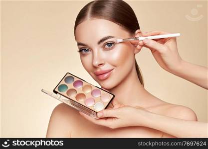 Makeup Artist applies Eye Shadow. Beautiful Woman Face. Perfect Makeup. Make-up detail. Beauty Girl with Perfect Skin. Nails and Manicure. Eye Shadow Palette