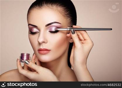 Makeup artist applies eye shadow. Beautiful woman face. Perfect makeup. Makeup detail. Beauty girl with perfect skin. Nails and manicure