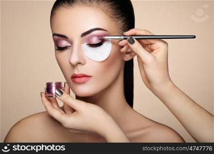 Makeup artist applies eye shadow. Beautiful woman face. Perfect makeup. Makeup detail. Beauty girl with perfect skin. Nails and manicure