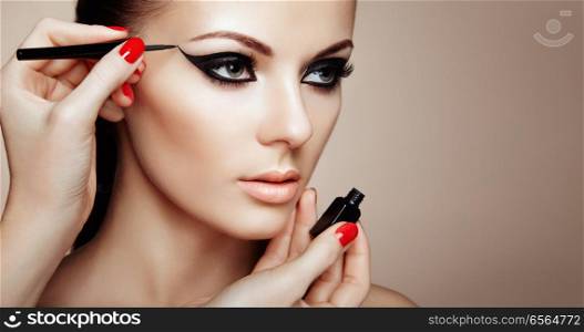 Makeup Artist Applies Eyeshadow. Beautiful Woman Make-up Eye with Black Liner. Fashion Makeup Arrows. Red Nails Perfect Skin