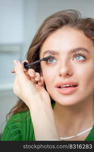 Makeup artist applies mascara on eyelash of young caucasian woman in beauty salon. Soft focus. Defocused.. Makeup artist applies mascara on eyelash