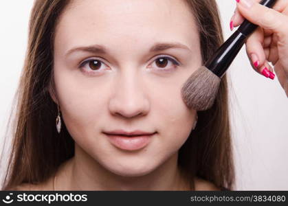 Makeup artist applies powder on the face of a beautiful young girl in the makeup