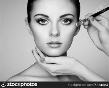 Makeup artist applies skintone. Beautiful woman face. Perfect makeup. Skincare foundation. Black and white