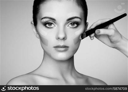 Makeup artist applies skintone. Beautiful woman face. Perfect makeup. Skincare foundation. Black and white