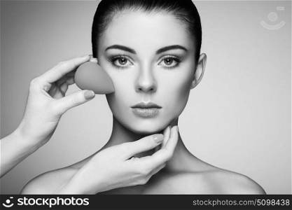 Makeup artist applies skintone. Beautiful woman face. Perfect makeup. Skincare foundation. Sponge makeup artist. Black and White photo