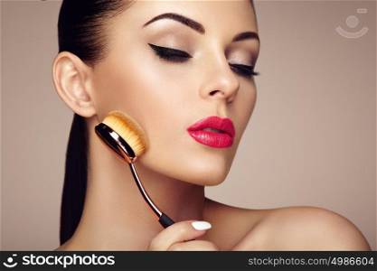 Makeup artist applies skintone with brush. Beautiful woman face. Perfect makeup. Skincare foundation. Brushes makeup artist