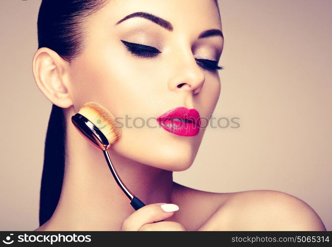 Makeup artist applies skintone with brush. Beautiful woman face. Perfect makeup. Skincare foundation. Brushes makeup artist