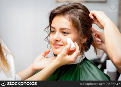 Makeup artist applying cream blush foundation tube on the cheek of the young caucasian woman in a beauty salon. Makeup artist applying cream blush foundation tube on the cheek of the young caucasian woman in a beauty salon.