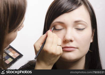 Makeup artist deals makeup on the model&#39;s face. She paints the shadows of the upper eyelids model.