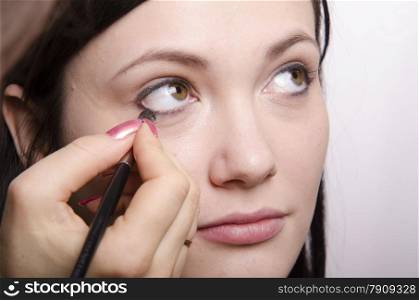 Makeup artist deals makeup on the model&#39;s face. She paints eyelashes model.