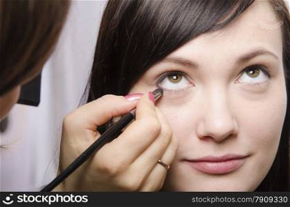 Makeup artist deals makeup on the model&#39;s face. She paints eyelashes model.