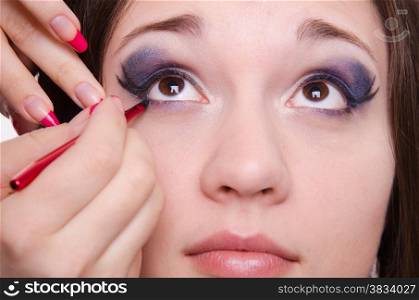 Makeup artist draws arrows beautiful young girl in the makeup