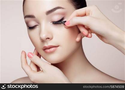 Makeup artist glues eyelashes. Beautiful woman face. Perfect makeup. Beauty fashion. Eyelashes. Cosmetic Eyeshadow