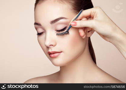 Makeup artist glues eyelashes. Beautiful woman face. Perfect makeup. Beauty fashion. Eyelashes. Cosmetic Eyeshadow