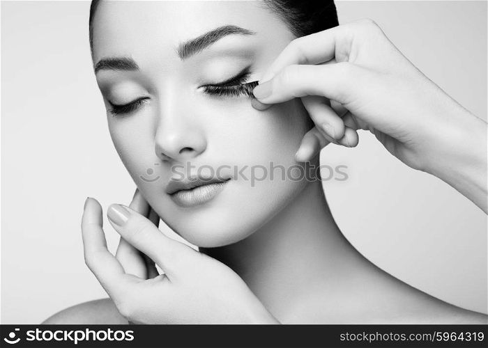 Makeup artist glues eyelashes. Beautiful woman face. Perfect makeup. Beauty fashion. Eyelashes. Cosmetic Eyeshadow