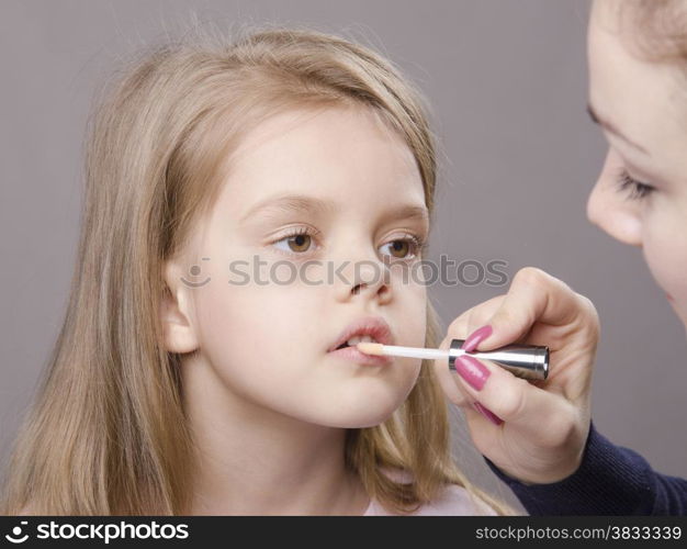 Makeup artist in the process of makeup causes Shine on the lips five year old girl