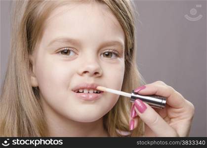 Makeup artist in the process of makeup causes Shine on the lips five year old girl