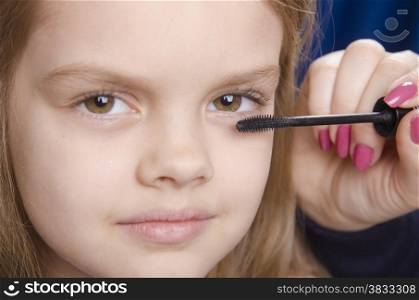 Makeup artist in the process of makeup colors eyelashes on the face five year old girl