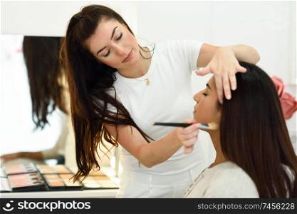 Makeup artist making up an African young woman in a beauty center.. Beauty and Aesthetic concepts.. Makeup artist making up an African young woman in a beauty center