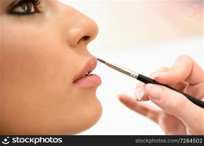 Makeup artist making up lips of an African young woman in a beauty center.. Beauty and Aesthetic concepts.