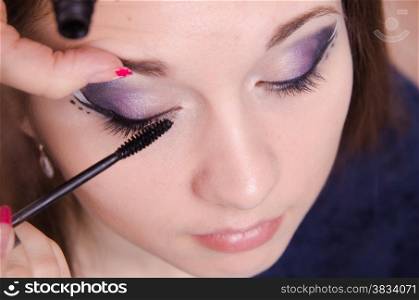 Makeup artist paints eyelashes of a beautiful young girl in the makeup
