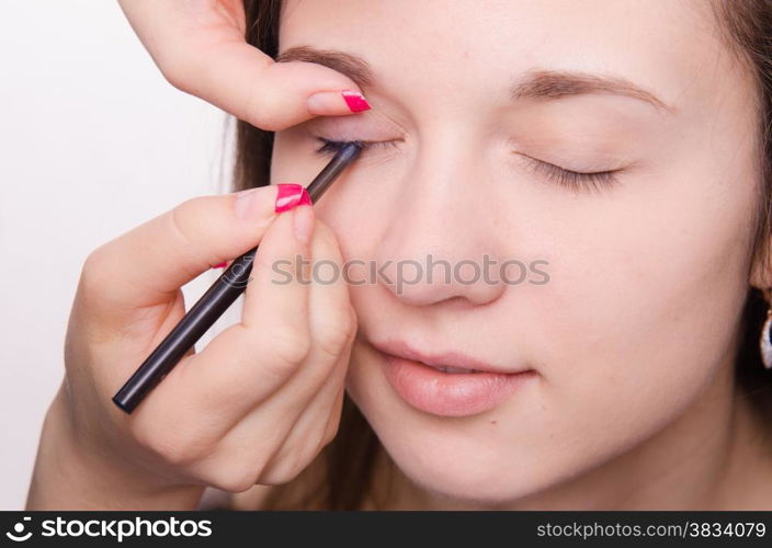 Makeup artist paints eyelashes of a beautiful young girl in the makeup