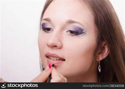 Makeup artist paints her lips a beautiful young girl in the makeup