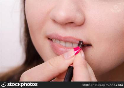 Makeup artist paints her lips a beautiful young girl in the makeup
