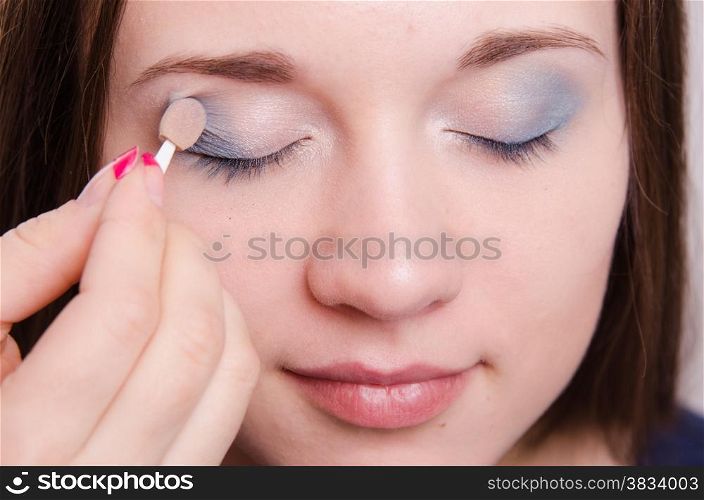 Makeup artist paints the eyelids of a beautiful young girl in the makeup