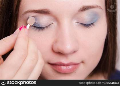 Makeup artist paints the eyelids of a beautiful young girl in the makeup