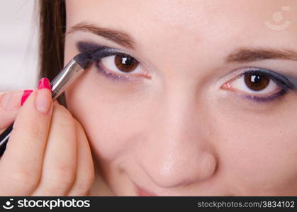 Makeup artist paints the eyelids of a beautiful young girl in the makeup