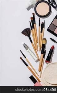 Makeup brushes and cosmetic products on a white background, flat lay