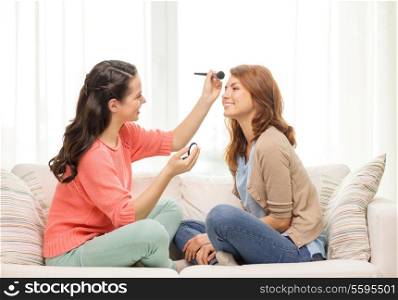 makeup, friendship and leisure concept - two smiling teenage girls applying make up at home