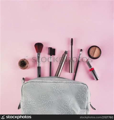 makeup products spilling out bag pink background