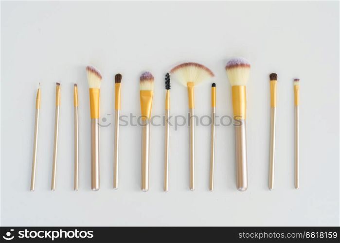 Makeup silver and gold brushes row on white background. Make up brushes
