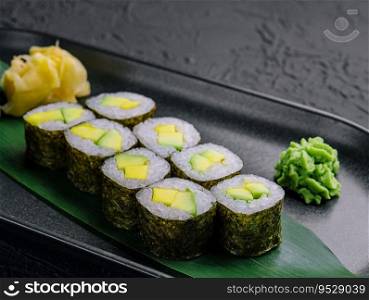Maki sushi roll with avocado on black plate