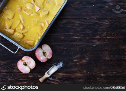 Making an apple pie. Raw dough in a baking dish, apple and sugar on the wooden background. Making an apple pie. Raw dough in a baking dish, apple and sugar on the wooden table