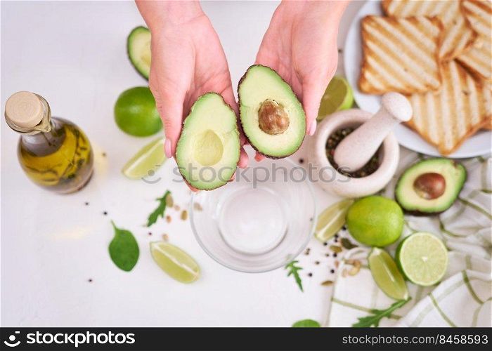 Making avocado toast - Woman hold fresh ripe halved avocado.. Making avocado toast - Woman hold fresh ripe halved avocado