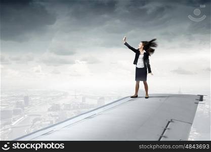Making best selfie photo. Businesswoman standing on airplane wing and taking selfie