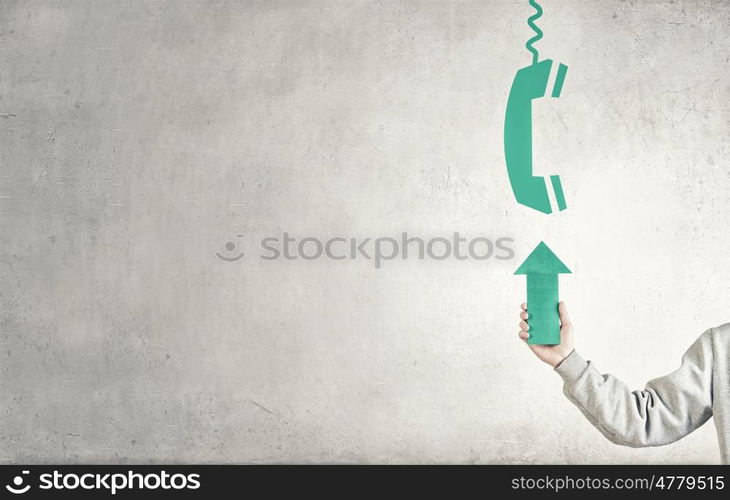 Making calls. Hand of businessman holding green arrow and pointing at calls sign