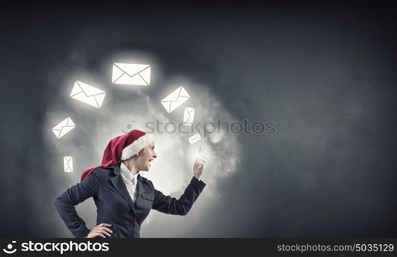 Making Christmas calls. Woman in suit and Santa hat talking on mobile phone