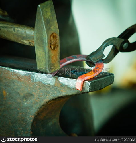 Making decorative element in the smithy on the anvil. Hammering glowing steel. Blacksmith forges a hot horseshoe.