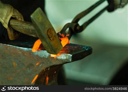 Making decorative element in the smithy on the anvil. Hammering glowing steel. Blacksmith forges a hot horseshoe.