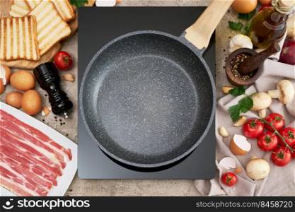 Making fried eggs and bacon - frying pan on induction hob and ingredients at domestic kitchen.. Making fried eggs and bacon - frying pan on induction hob and ingredients at domestic kitchen