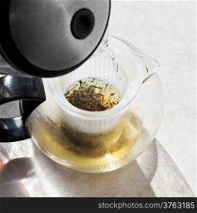 making green tee in teapot with boiling water