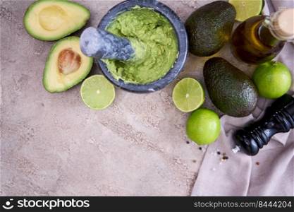 making guacamole - crushed avocado in marble mortar on grey concrete table.. making guacamole - crushed avocado in marble mortar on grey concrete table